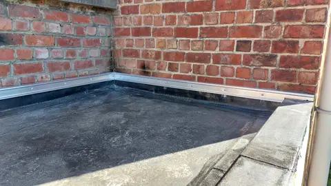 Toiture plate en EPDM : relevés de la membrane contre les murs en briques, fixés par un profilé en aluminium