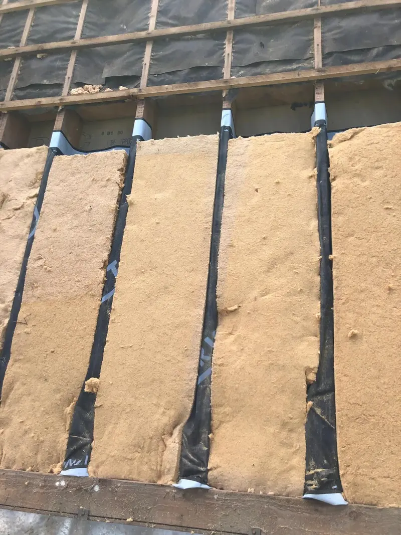 Panneaux de fibre de bois entre les chevrons, joints fermés par des bandes adhésives noires