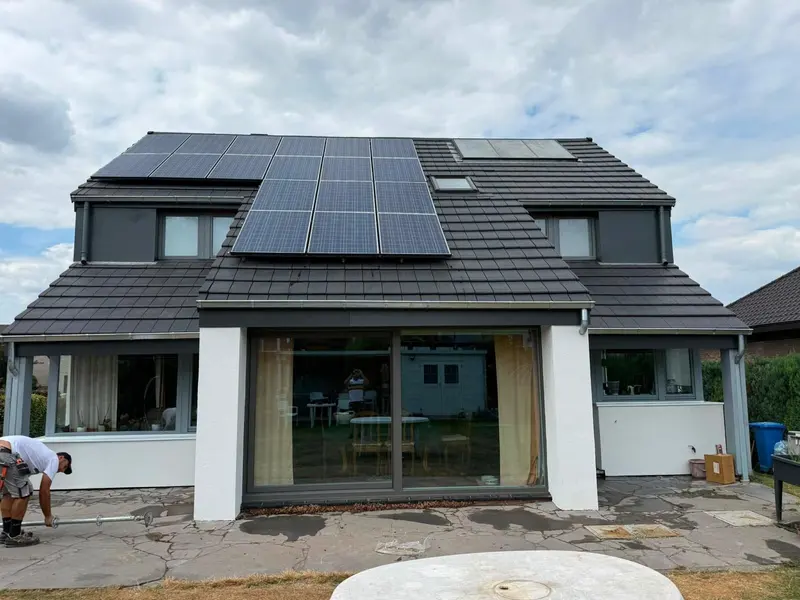 Maison rénovée vue du jardin : toiture neuve en tuiles plates anthracite avec panneaux solaires, lucarne et corniches en zinc