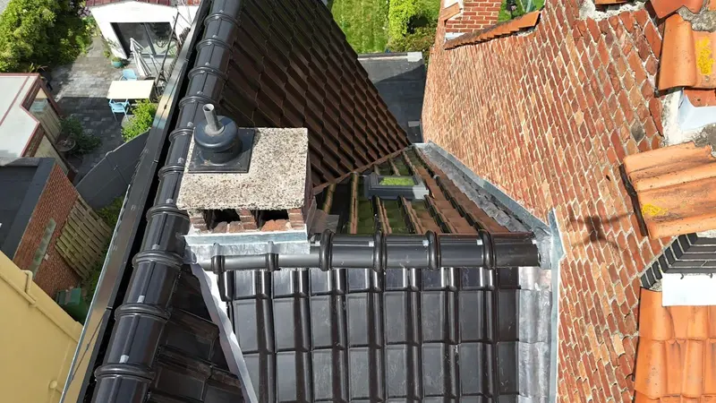 Souche de cheminée en briques avec chapeau neuf, solin en zinc et tuiles noires neuves autour, vue du drone