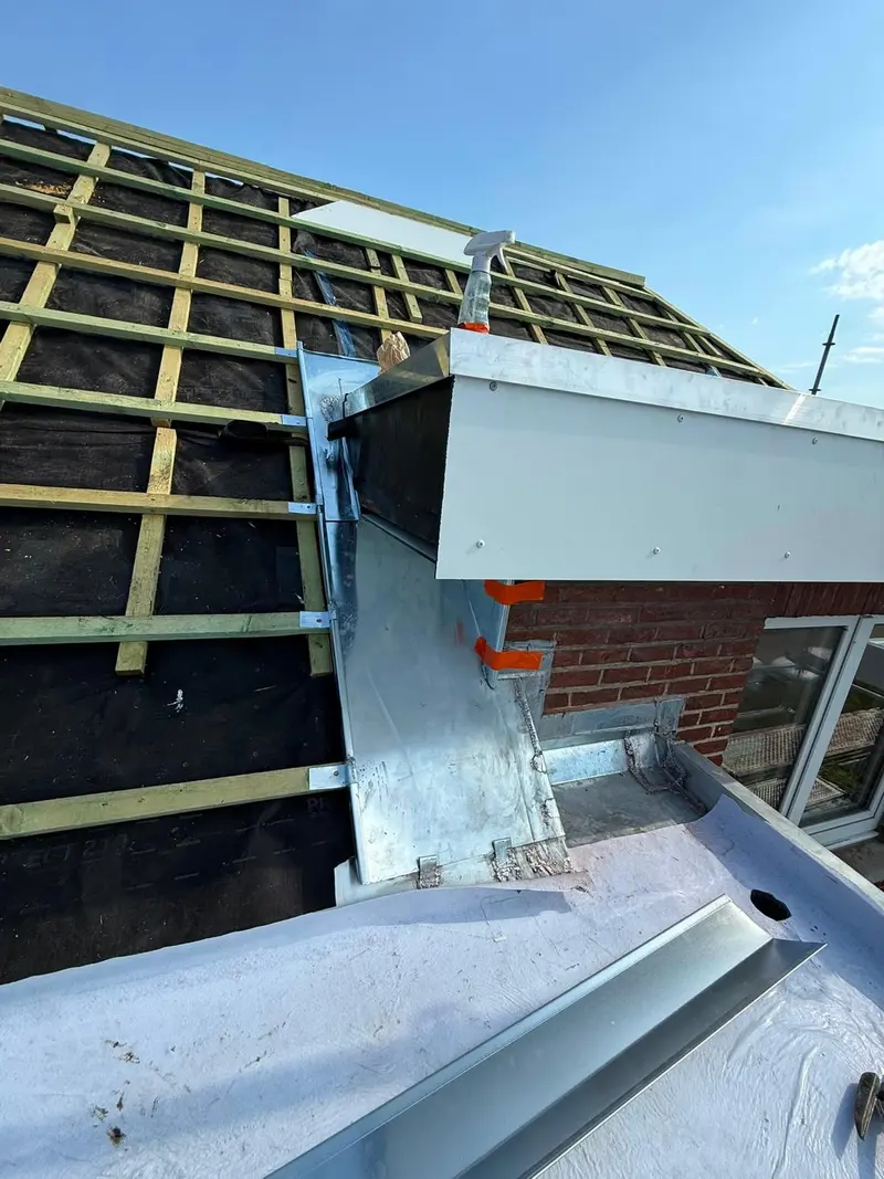 Sous-toiture noire et contre-lattes, raccord en zinc contre le mur d’une lucarne en briques, chantier en cours