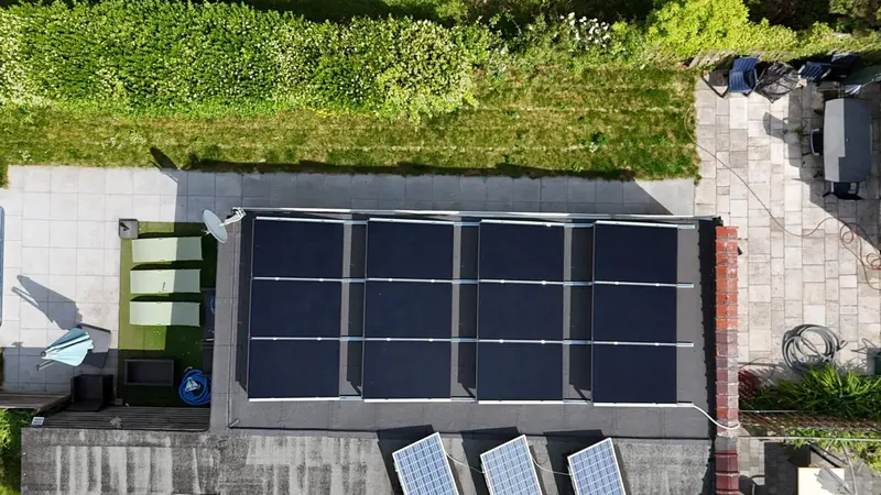 Toit plat avec panneaux solaires alignés et rive en aluminium, jardin en contrebas, vue du drone