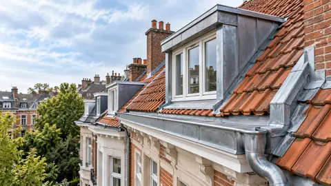 Toiture en tuiles avec lucarne, chéneau et descente d’eau pluviale en zinc, typique des maisons bruxelloises