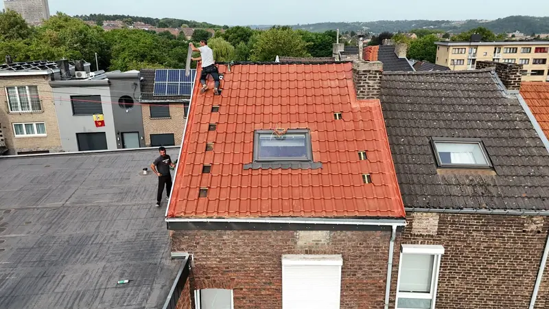 Toiture neuve en tuiles rouges avec fenêtre de toit vue du drone, maison de rangée en briques, couvreur au faîtage